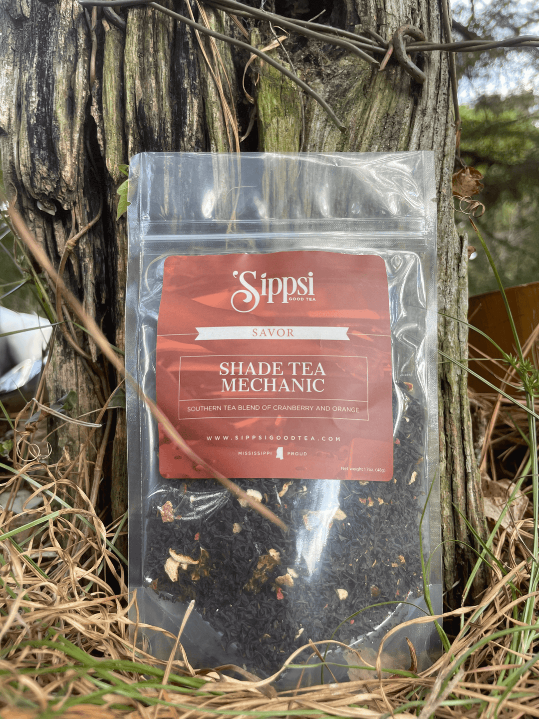 Sippsi Good Tea Shade Tea Mechanic resealable pouch with an orange label, standing against a tree outdoors.