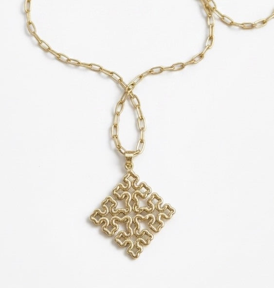 Gold-tone Bela 2.0 necklace with an ornate Ethiopian cross pendant suspended from an oval-link chain on white