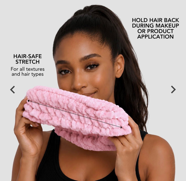 Model holding a pink Hairbrella spa headband stretched between both hands to demonstrate its flexible fit.