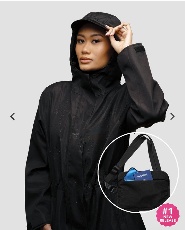 Model wearing a black hooded Hairbrella rain jacket, with an inset showing a black shoulder bag holding small essentials.